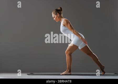 Athletic woman doing pilates stretching for balance and flexibility, modern workout for healthy body and posture Stock Photo