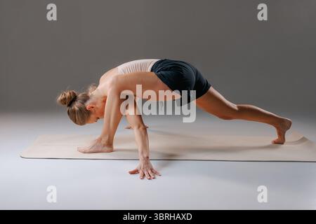 Focused woman performing pilates and stretching exercises for flexibility, strength, and healthy posture at home Stock Photo