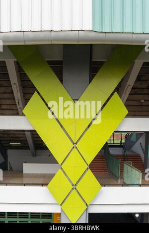Architectural details of a modern stadium in Bekasi. A bright lime green V-shaped geometric pattern on the exterior facade of the sports arena. Stock Photo