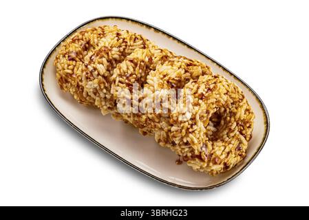 High angle view group of crispy homemade sweet rice crackers with cane sugar syrup in brown ceramic tray with dark edge isolated on white background w Stock Photo