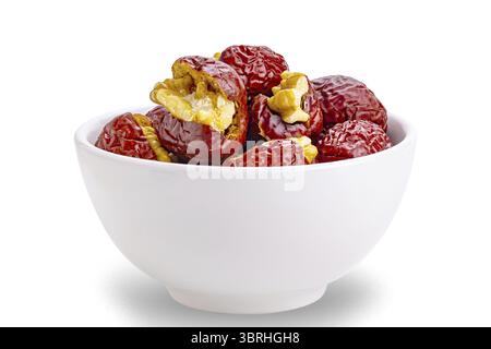 Side view of crunchy walnut stuffed red chinese jujube in white ceramic bowl isolated on white background with clipping path Stock Photo