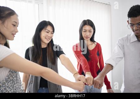 Team building group of people Asian business hands join empower partnership teams fist bump circle for teamwork Stock Photo