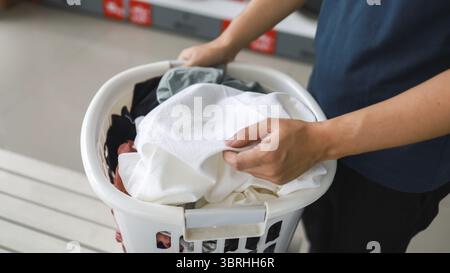 Man doing launder holding basket with dirty laundry of the washing machine in the public store. laundry clothes concept Stock Photo
