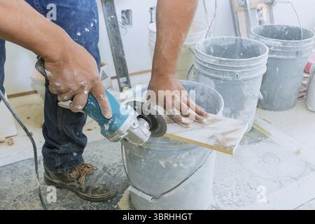 A construction worker cutting a tile using grinder round the ceramic disc Stock Photo