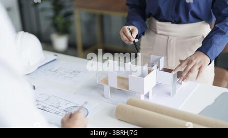 House model on Buleprint construction drawing and drawing equipment stationary Architect analyzing house model house modern in hand Architect Design C Stock Photo