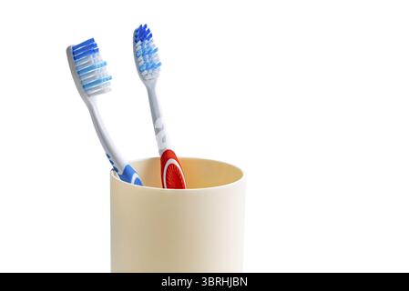 View of new toothbrushes red and blue handle in plastic cup isolated on white background with clipping path Stock Photo