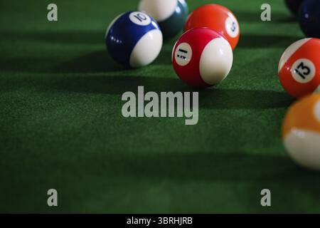 Man's hand and Cue arm playing snooker game or preparing aiming to shoot pool balls on a green billiard table. Colorful snooker balls on green frieze Stock Photo