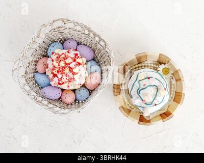 Sweet Easter cakes and colorful Easter eggs in the wooden baskets on the white background. Top view Stock Photo