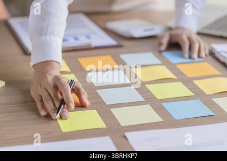 Business People working on sticky notes creative writing down ideas on sticky note notes professional investor start up project business Stock Photo