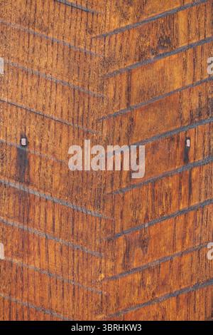 Light brown wooden panel with inlaid herringbone pattern, visible nails, and varying shades of intricate wood grain. Rustic and weathered surface. Stock Photo