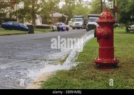Water flowing from in open red fire hydrant is wet from the spray Stock Photo