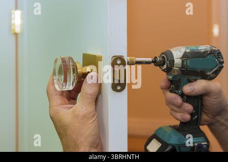 Man repairing the doorknob closeup of worker hands installing new door locker Stock Photo