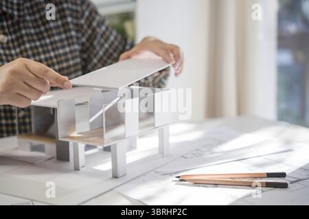House model on Buleprint construction drawing and drawing equipment stationary Architect analyzing house model house modern in hand Architect Design C Stock Photo