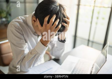 Asian Business man tiredness and stress while having headache. Painful men are stressed at work in office Stock Photo