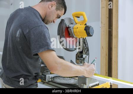Carpenter cutting wooden trim board on with circular saw. Woodworker works on remodeling home Stock Photo