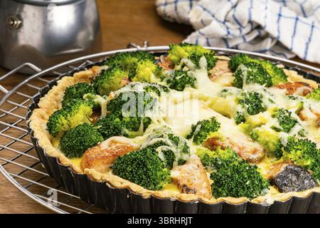 Closeup view of freshly baked delicious french food broccoli and salmon quiche on cooling rack on wooden table Stock Photo