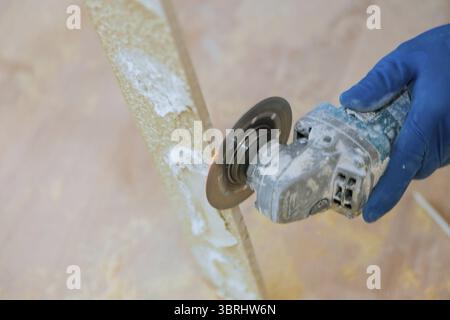 A construction worker cutting a tile using grinder round the ceramic disc Stock Photo