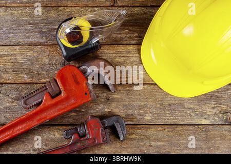 Yellow hard hat and leather work gloves and wrench construction of bunch of hand tools and helmet Stock Photo