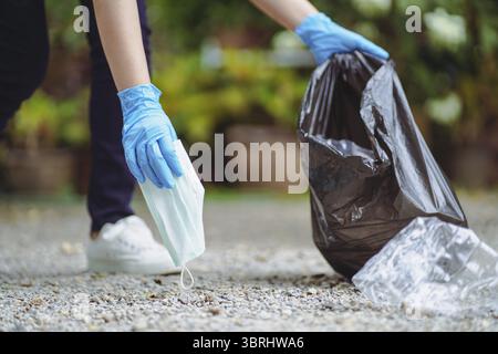 Volunteer charity woman hand holding surgical protective mask during the coronavirus pandemic. Covid-19. throwing away used protective face mask in ga Stock Photo
