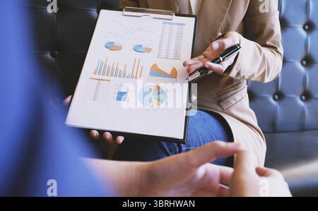 Businesswoman in suit making presentation explaining charts. and discussing a new business project with the members Stock Photo