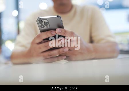 Relaxed young asian man using smart phone spending time checking news social media Stock Photo