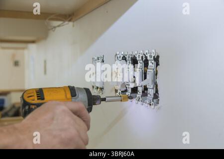 Work on installing electrical outlets with electrical wires and connector installed in plasterboard drywall Stock Photo