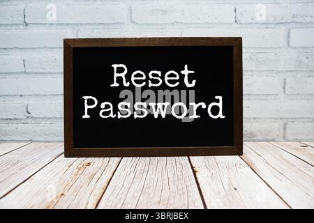 Reset Password text written on chalkboard standing on wooden background Stock Photo