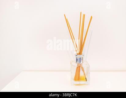 Minimalist home fragrance reed diffuser with orange sticks on white background. Stock Photo
