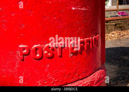 Close-up of a Vibrant Red Royal Mail Post Box with 'POST OFFICE' Embossed on the Side Stock Photo