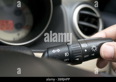 Man driving hands pushing turn on light switch on steering wheel in the car selective focus. safety driving concept Stock Photo