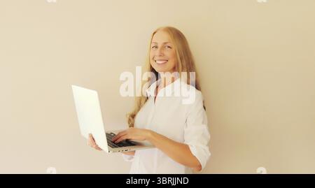 Happy caucasian middle-aged woman working with laptop at home Stock Photo