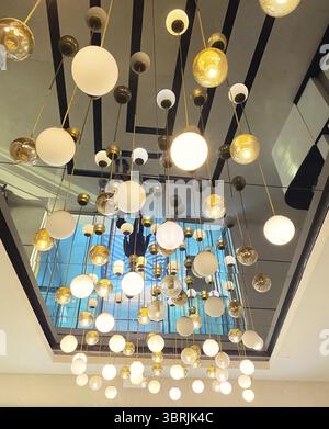 Many hanging lights, pendant round ball-shaped lamps on the mirror ceiling, interior decor Stock Photo