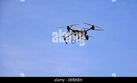 Industrial drone flying in clear blue sky. Agricultural drone flying for crop monitoring. Stock Photo