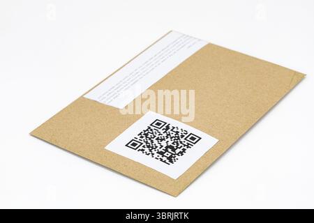 A brown envelope with qr code label is placed on white surface, showcasing modern and efficient way to share information. envelope simple design Stock Photo