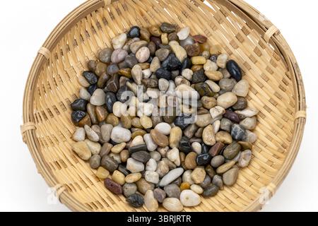 A wicker basket filled with mixed river stones showcases variety of colors and textures, creating natural and earthy aesthetic. stones are smooth Stock Photo