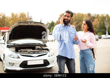 Indian man talking phone while woman standing beside him with worried expression Stock Photo