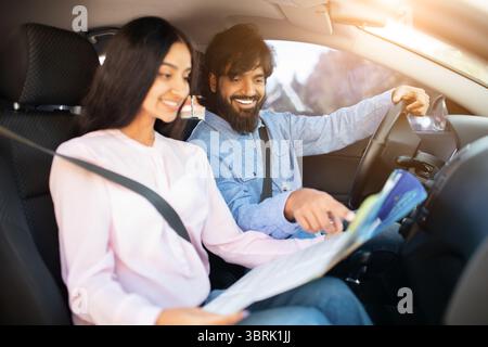 Man and woman happily planning route using map while sitting in car Stock Photo