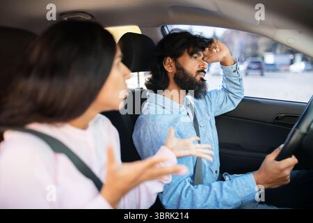 Indian couple arguing inside car, woman speaking while man looks stressed Stock Photo