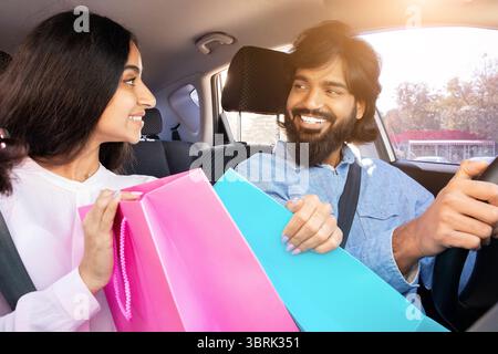 Indian couple smiling while sitting in car with shopping bags Stock Photo