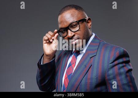 Confident african businessman in modern glasses and striped suit showing style, success, and leadership in business Stock Photo