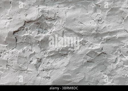 Close up view of a textured concrete wall, showcasing its rough and uneven surface in shades of white and gray, creating a unique visual background Stock Photo