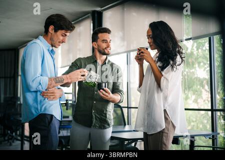 Happy creative diverse colleagues having fun while talking and drinking coffee, tea in working break Stock Photo