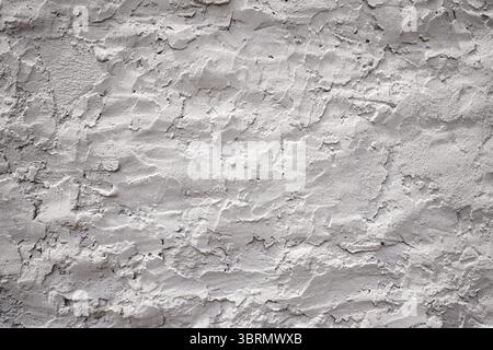 Close up view of a textured concrete wall, showcasing its rough and uneven surface in shades of white and gray, creating a unique visual background Stock Photo