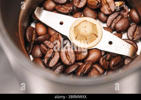 Coffee beans in grinder. Close-up of fresh roasted beans. Manual grinding tool with brown espresso ingredients. Caffeine drink preparation concept. Stock Photo