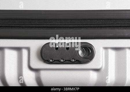 Closeup of travel suitcase zipper lock. Secure luggage protection detail. Black combination lock on silver hard shell. Travel accessory safety. Stock Photo