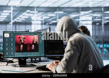 System administrator in server hub coding AI program turning text prompt into photos. Hooded man in data center using computer to build text to image artificial intelligence generative models Stock Photo