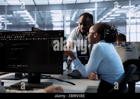 Team of engineers talking in server hub, ensuring compliance with industry standards and regulatory requirements. Data center teamworking colleagues conducting security audits Stock Photo