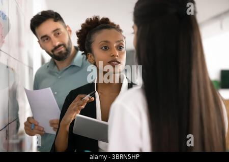 African woman engaging in strategic planning session with teammates Stock Photo