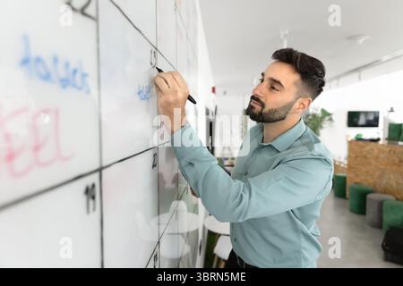 Young Hispanic man writing on large whiteboard Stock Photo