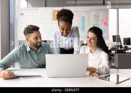 Marketing department members gathered in office working together using laptop Stock Photo